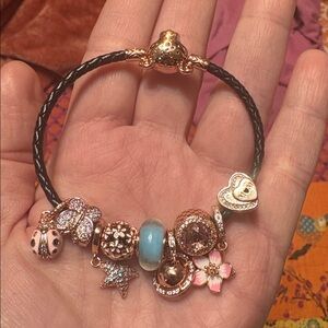 Pandora black braided bracelet with rose gold plated lioness clasp and 9 charms